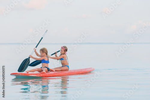 Little cute girls swimming on surfboard during summer vacation © travnikovstudio
