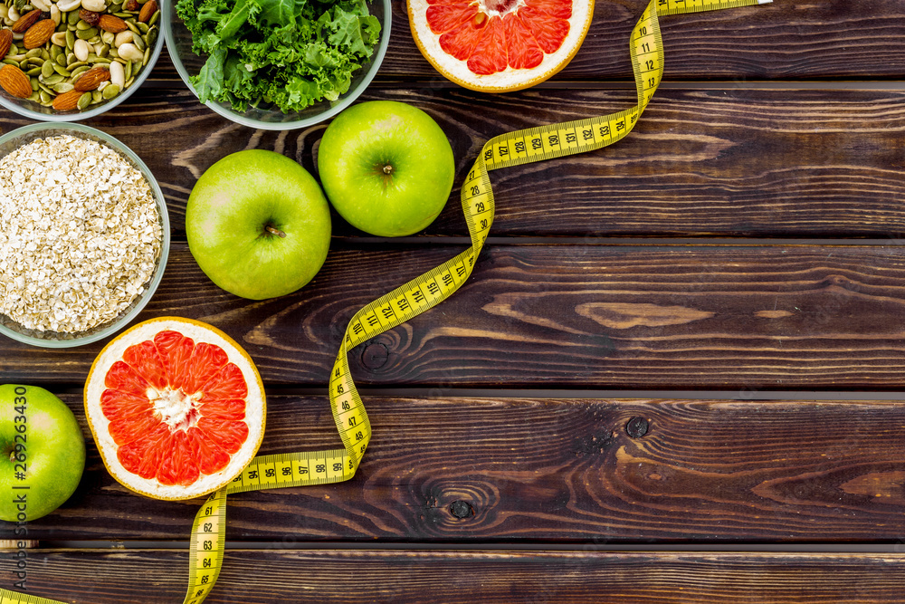 Diet for weight loss concept with measuring tape, greenary and oat on wooden background top view copy space Diet for weight loss concept with measuring tape, greenary and oat on wooden background top view copy space