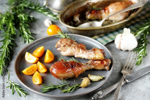 Baked Chicken Legs with Fresh Rosemary and yellow cherry tomatoes . keto dish rich in fats and protein. the chicken is placed in a baking dish on a pillow of rosemary branches.