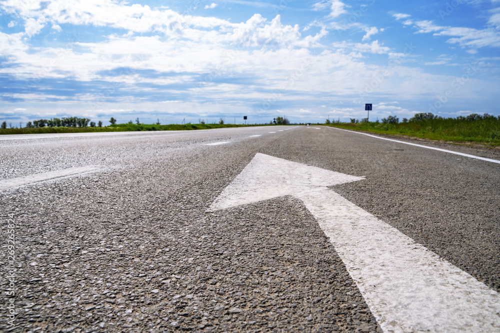 Forward igns on the road. White painting in turn left direction arrow symbol on black asphalt road background and against the blue sky