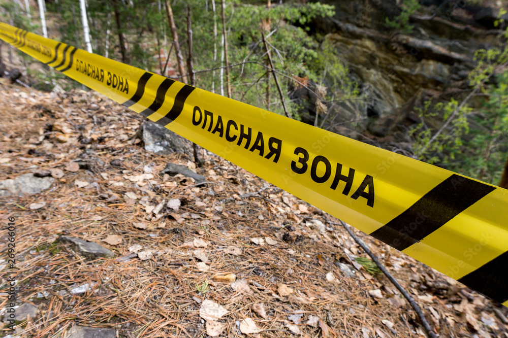 Danger zone in cyrillic on the footpath in forest. Warning sign in forest Danger zone in cyrillic on the footpath in forest. Warning sign in forest