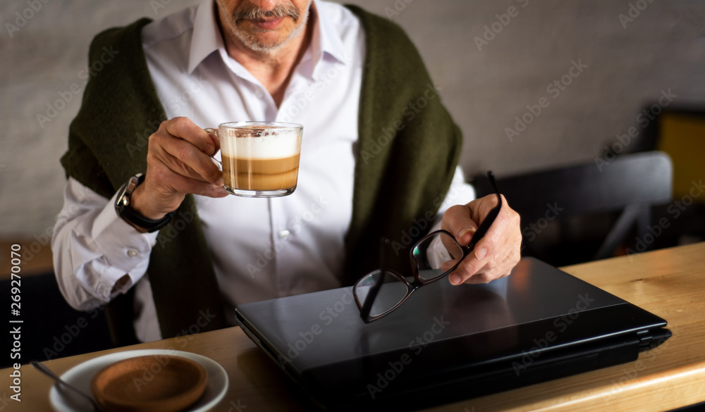 Senior man using laptop and having coffee in the bar Senior man using laptop and having coffee in the bar