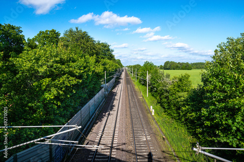 Bahn Gleise, Schienen führen gerade zum Horizont bei blauem Himmel durch grüne Natur