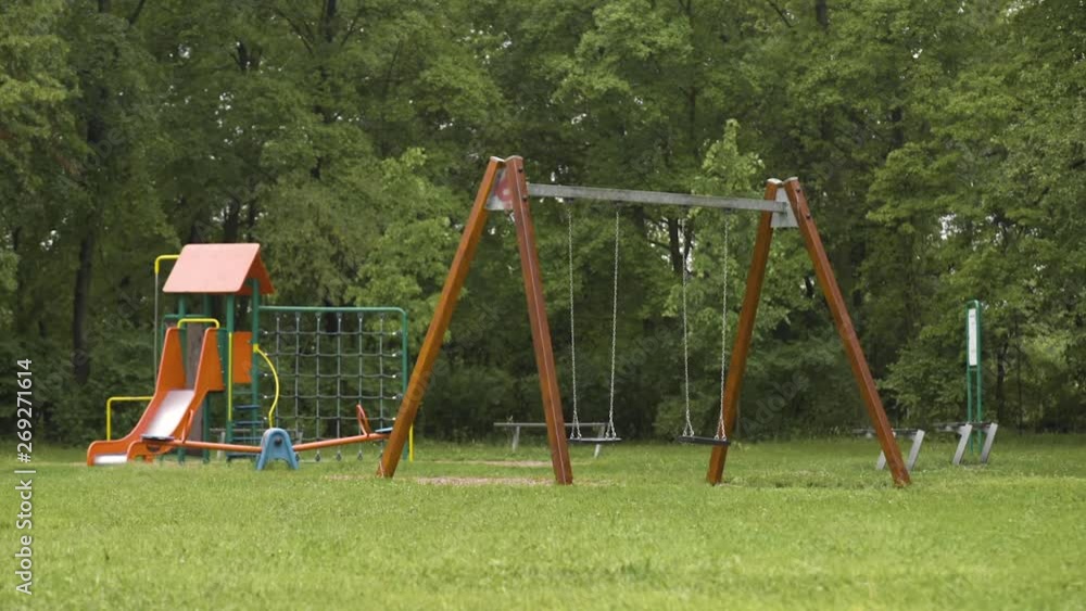 Empty playground after rain. Swing got wet in raindrops. Summer or spring rainy day. No people. No children. Empty playground after rain. Swing got wet in raindrops. Summer or spring rainy day. No people. No children.
