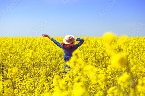 girl walking in a field of yellow rapeseed