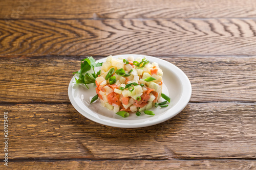 Potato salad with smoked salmon and green onion isolated on wooden background