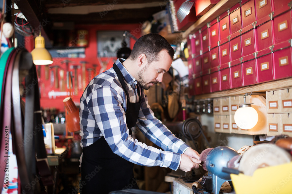 Fototapeta premium Male worker polishing buckle for belt