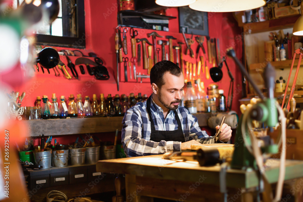 Male worker working on leather for belt in leather