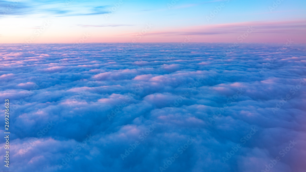 Beautiful pink sunrise over the clouds, view from the plane.