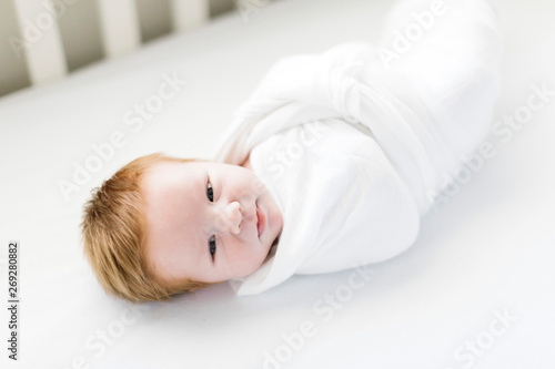 Swaddled baby boy in cot photo