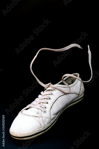 One walking shoes on black background. White leather fashion shoes with lace.
