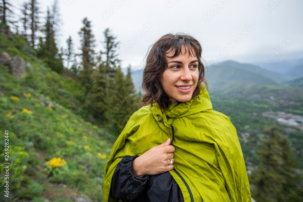 Young woman wearing green raincoat standing on mountain Young woman wearing green raincoat standing on mountain