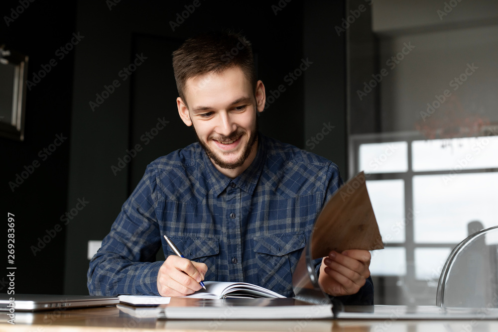 Smiling young businessman writing in note pad Smiling young businessman writing in note pad