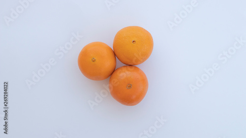 Three oranges placed next to each other lay on a white background viewed from an overhead angle from above.