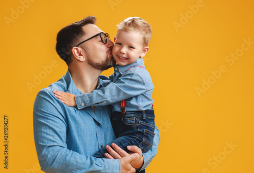happy father's day! cute dad and son hugging on yellow background photo