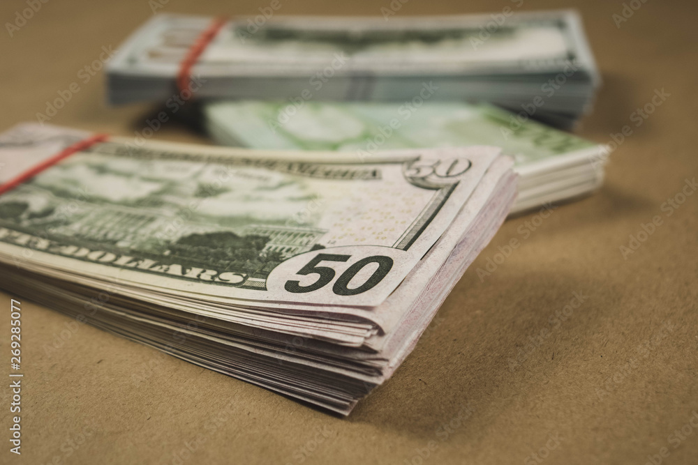 several wads of cash lying on top of each other on a beige background. several wads of cash lying on top of each other on a beige background.