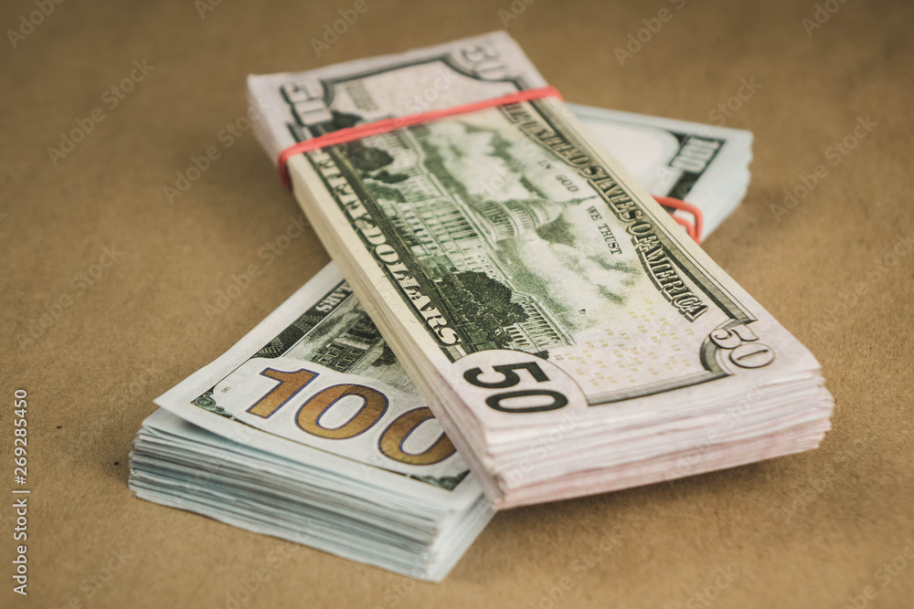 several wads of cash lying on top of each other on a beige background. several wads of cash lying on top of each other on a beige background.