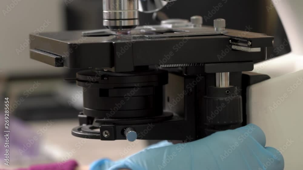 Medical laboratory worker using microscope for testing biological samples, examining liquid, professional equipment. Close-up, blurred background Medical laboratory worker using microscope for testing biological samples, examining liquid, professional equipment. Close-up, blurred background