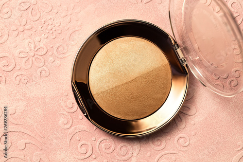 Powder on a pink background, macro image of cosmetics, two-tone bronzer and highlighter
