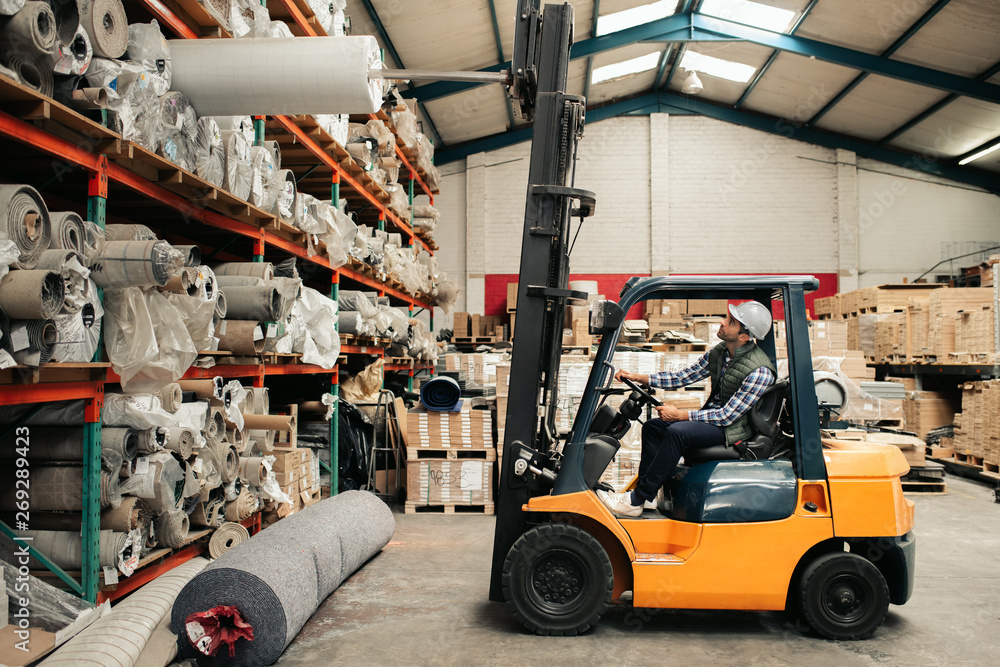 Forklift driver carefully moving stock around a large warehouse