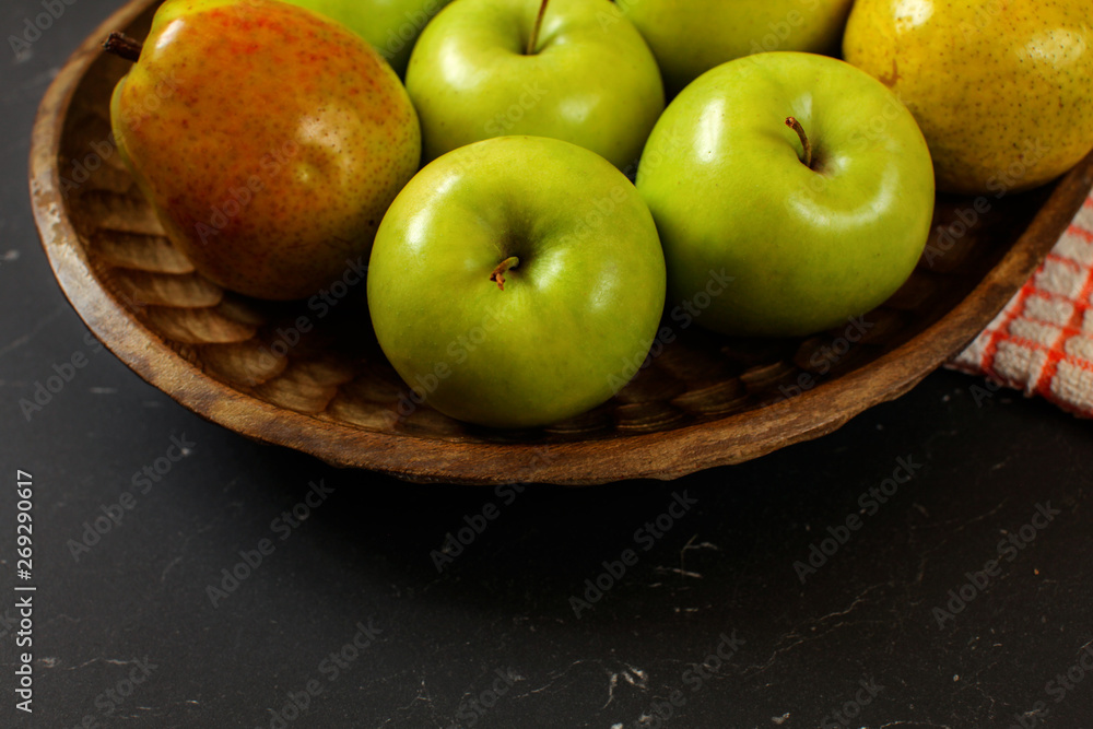 Close-up of apples and pears in wooden carved bowl on black board Close-up of apples and pears in wooden carved bowl on black board