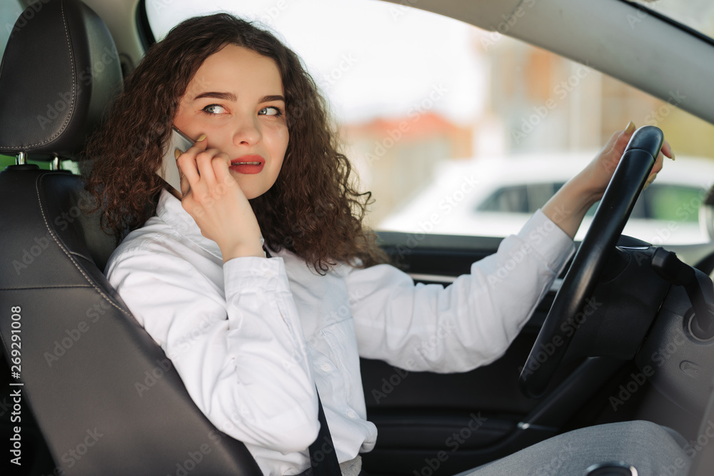 Portrait of business woman driver talking her mobile phone while driving car.