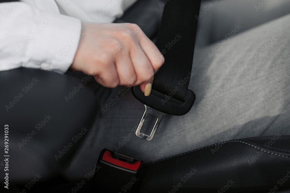 Women's hand fastens the seat belt of the car. Close your car seat belt while sitting inside the car before driving and take a safe journey. Closeup shot of female driver fastens seat belt. Women's hand fastens the seat belt of the car. Close your car seat belt while sitting inside the car before driving and take a safe journey. Closeup shot of female driver fastens seat belt.
