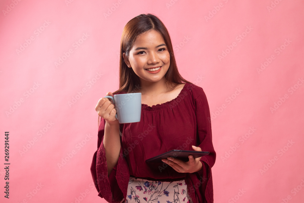 Young Asian woman with a computer tablet and coffee. Young Asian woman with a computer tablet and coffee.