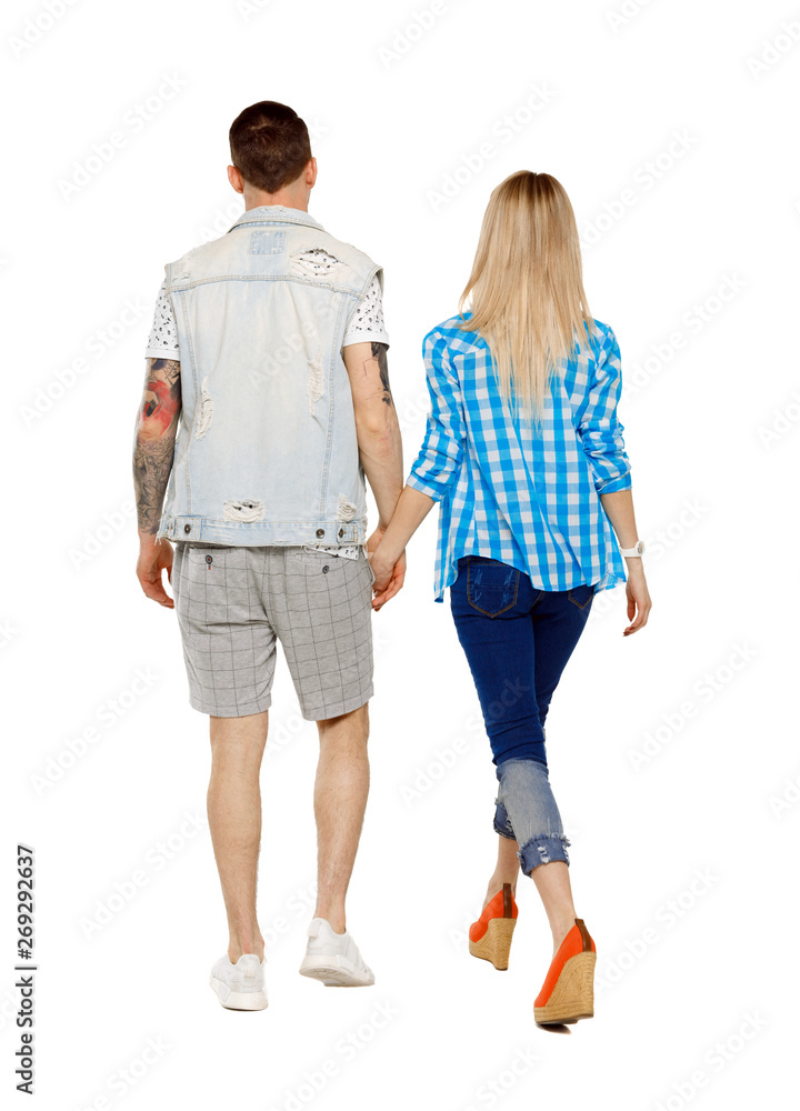 Back view of going couple. walking friendly girl and guy holdin Back view of going couple. walking friendly girl and guy holdin