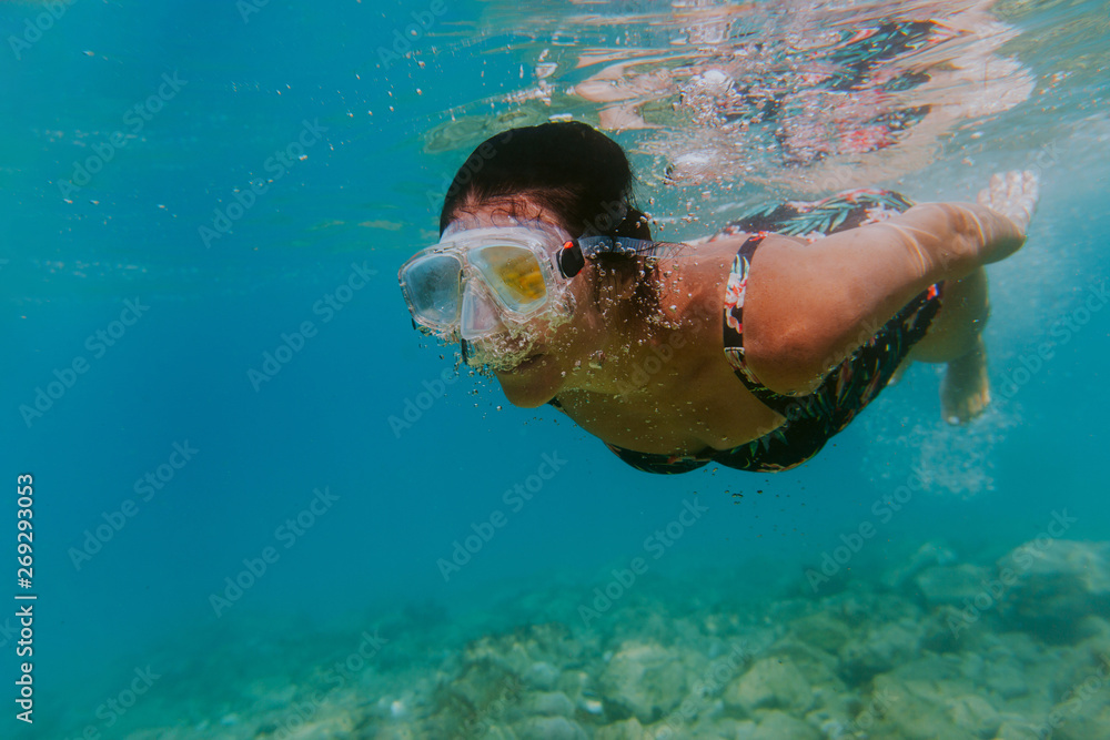Woman swimming in sea. Female swimmer wearing diving mask enjoying diving in shallow waters.