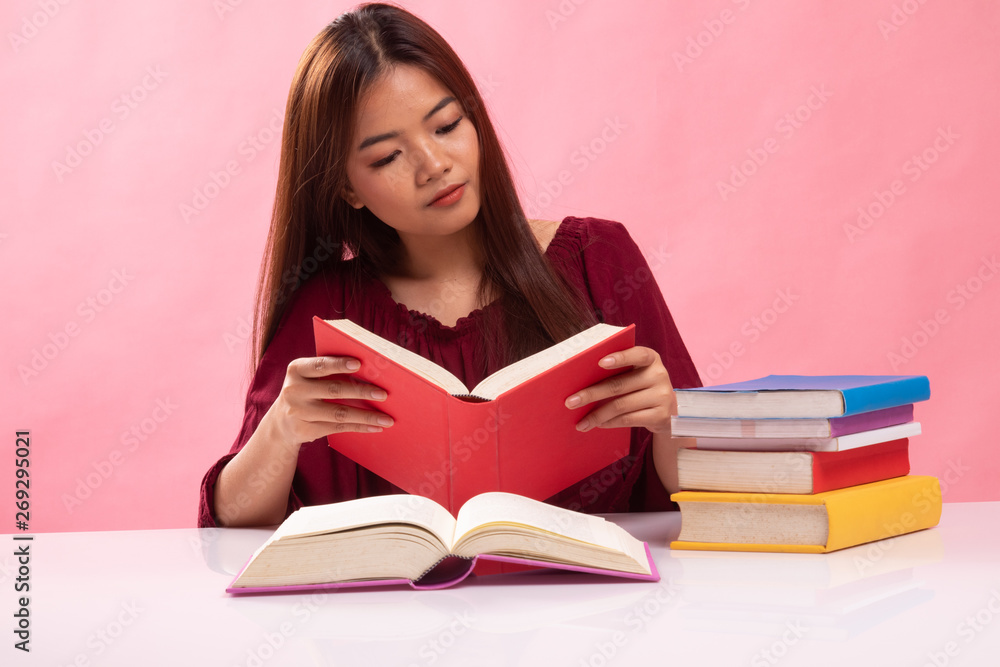 Young Asian woman read a book with books on table. Young Asian woman read a book with books on table.