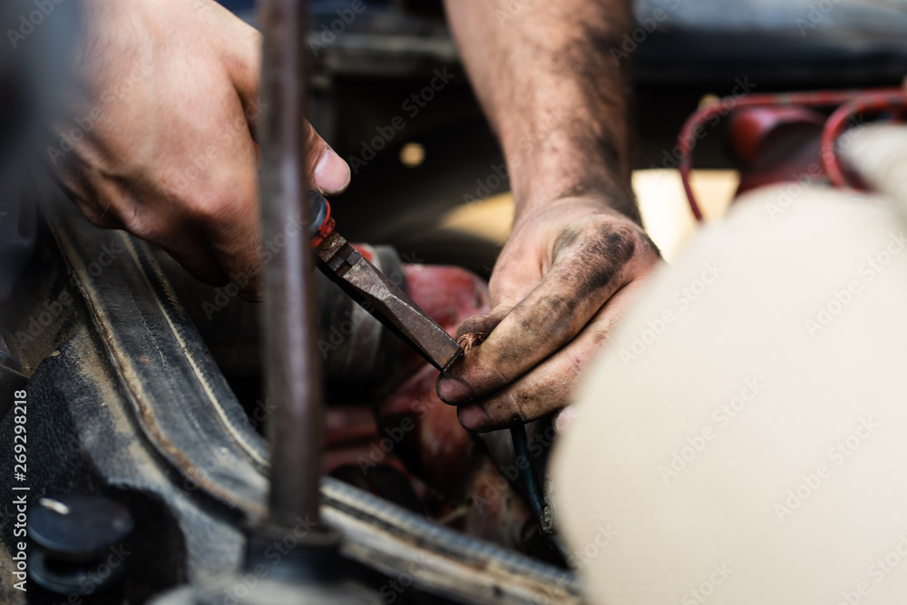 Obraz premium Close up on mechanic repair man electrician using hand tool combined pliers to connect copper wires on the motor engine block of the truck