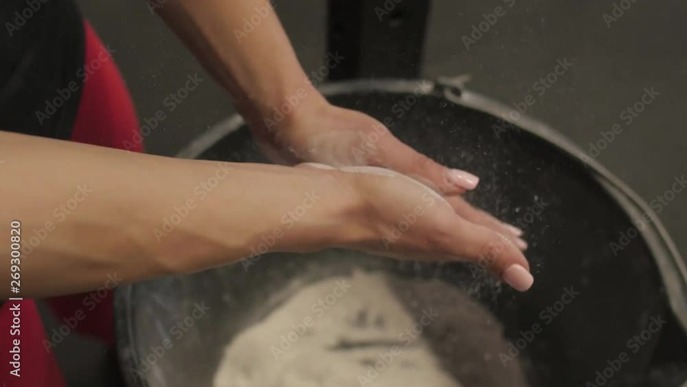 Athletic woman coating her hands in powder chalk magnesium at the gym Athletic woman coating her hands in powder chalk magnesium at the gym