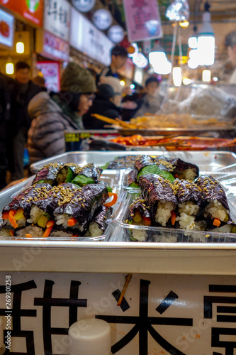 Korean-style gimbap (also known as 'kimbap') sushi rolls for sale among diners at lunch time in the famous, crowded Gwangjang Market in Seoul