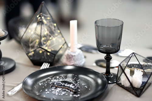Stylish table set with black crockery and original candles for wedding reception