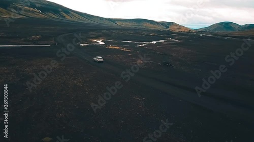 Drone shot of a vehicle traveling through the winding roads of iceland on F208 Road photo