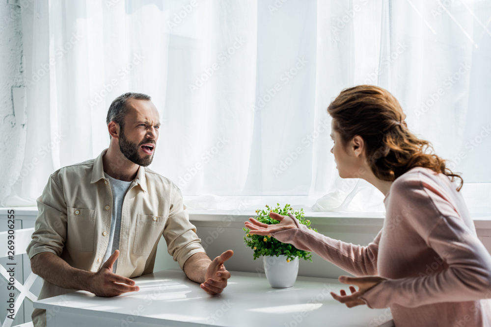 selective focus of angry man gesturing and looking at woman selective focus of angry man gesturing and looking at woman