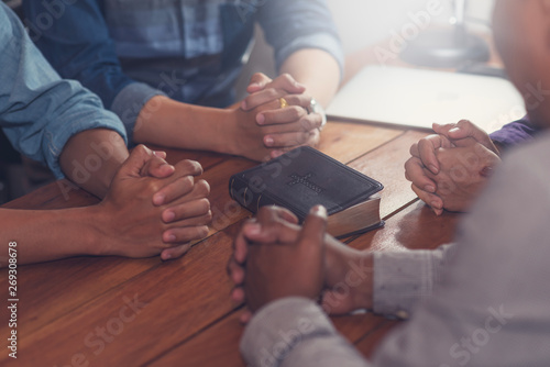 Christians and Bible study concept. Group of discipleship Studying the Word Of God in church and christians holding each others hand praying together photo