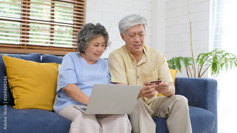 Fototapeta premium Senior asian couple shopping online by using laptop computer and credit card at home living room, Retirement people technology lifestyle