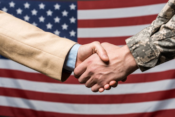 selective focus men shaking hands near american flag