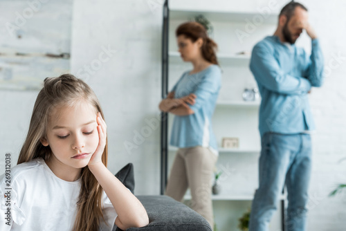 selective focus of sad kid near quarreling parents at home