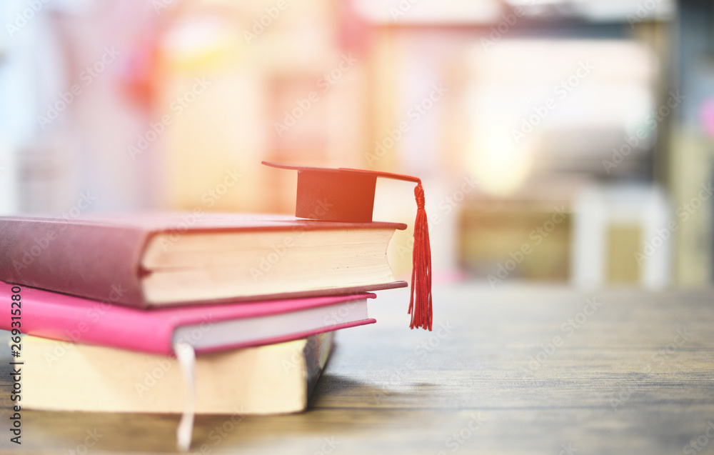 Education concept with graduation cap on a book on the wooden table Education concept with graduation cap on a book on the wooden table
