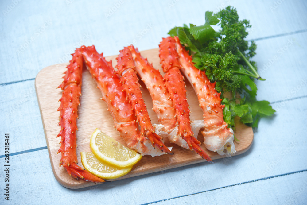 Alaskan King Crab Legs Cooked on wooden cutting board with lemon parsley - red crab hokkaido seafood served table Alaskan King Crab Legs Cooked on wooden cutting board with lemon parsley - red crab hokkaido seafood served table
