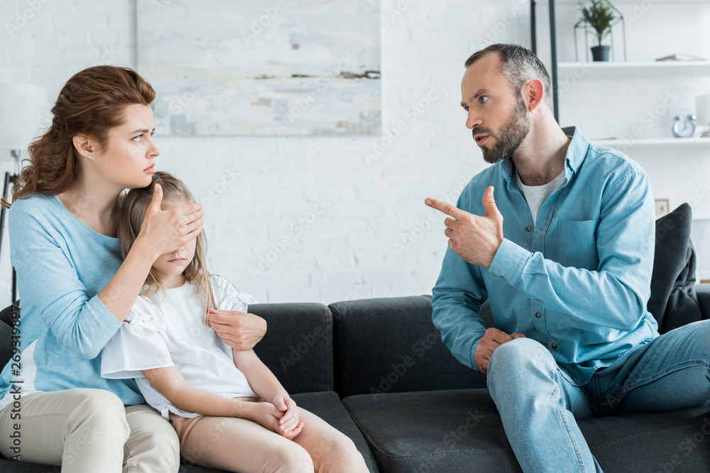 bearded man pointing with finger at wife while sitting on sofa bearded man pointing with finger at wife while sitting on sofa