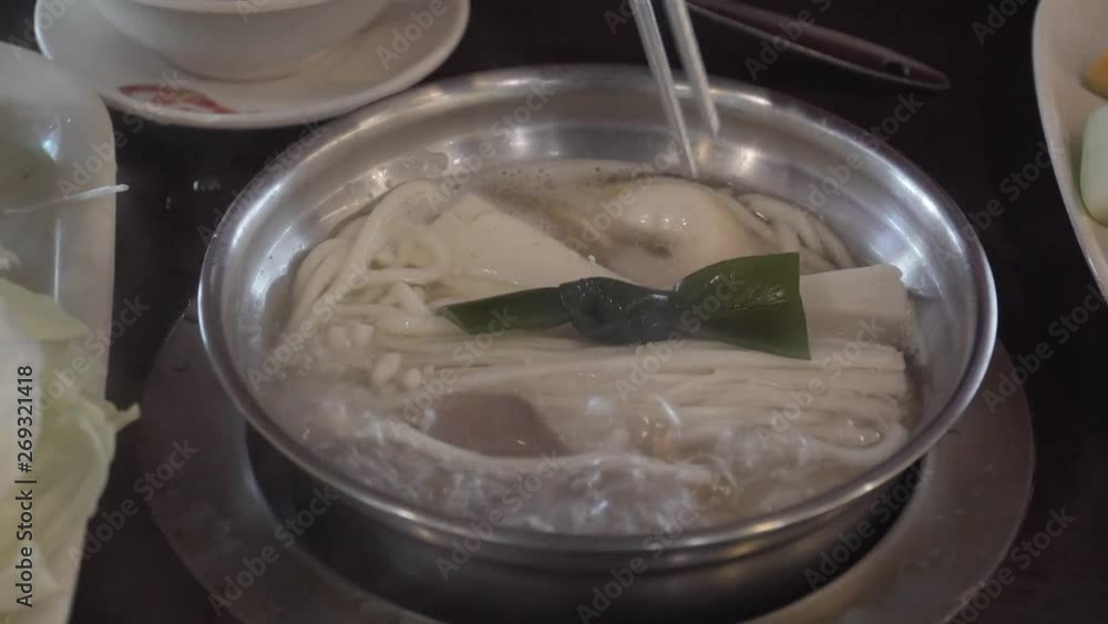 Hands Put Vegetables and Meat into Hot Pot. Eating at Chinese Restaurant Hands Put Vegetables and Meat into Hot Pot. Eating at Chinese Restaurant