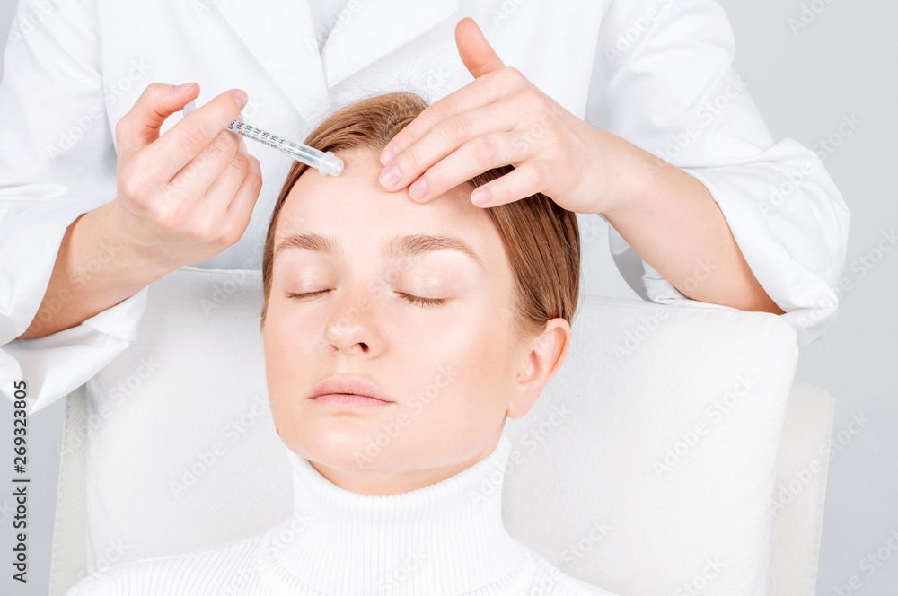 Woman is getting injection in forehead. Anti-aging treatment and face lift. Facial skin lifting injection to woman's face. Woman is getting injection in forehead. Anti-aging treatment and face lift. Facial skin lifting injection to woman's face.