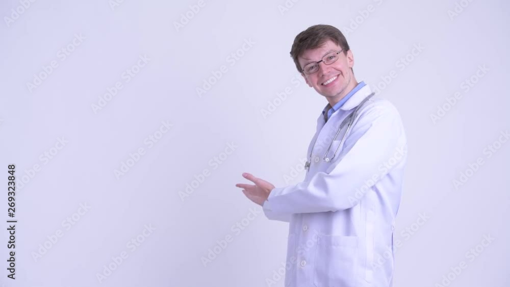 Happy young handsome man doctor presenting something to the back Happy young handsome man doctor presenting something to the back
