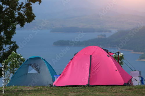 Colourful tent in the meadow outside. Pink camping tent in forest near a river.