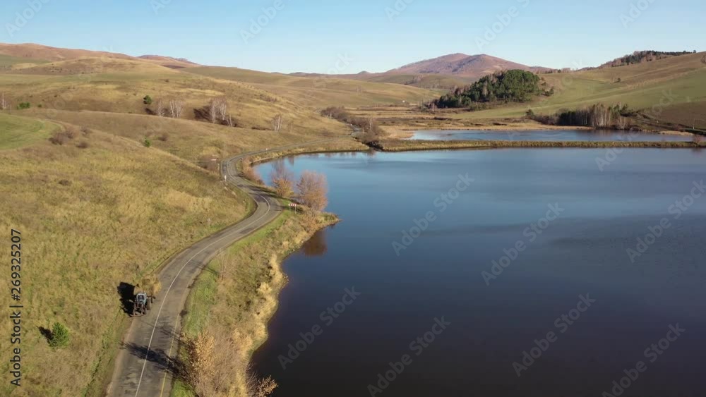 Flying over a hilly rural landscape with a winding road and fish ponds Flying over a hilly rural landscape with a winding road and fish ponds