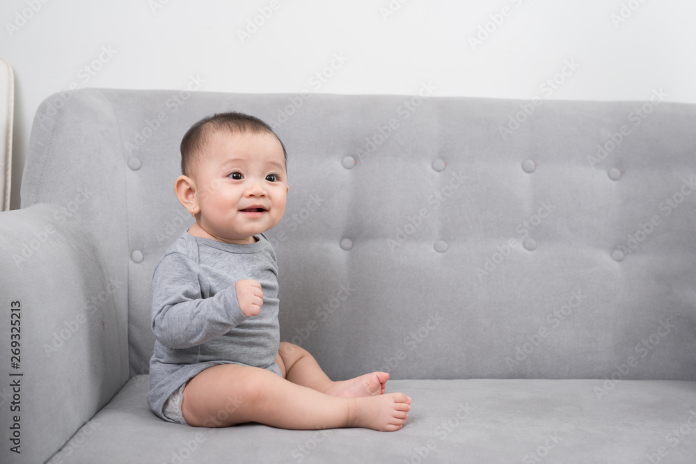 childhood, babyhood and people concept - happy little baby girl sitting on sofa at home childhood, babyhood and people concept - happy little baby girl sitting on sofa at home